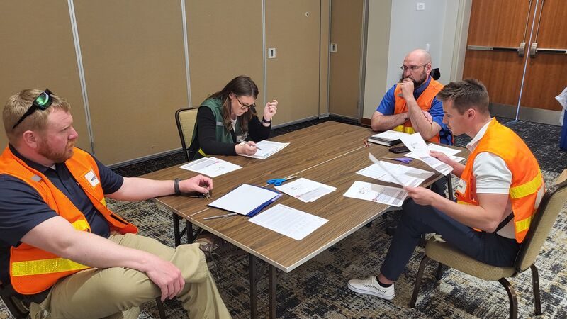 Mixed-discipline team working through SSAVEIM checklists and forms during a training exercise